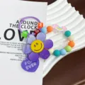 Kreativer Sonnenblumen-Schlüsselanhänger mit Smiley und bunter Perlenarmband-Verzierung - Lila