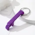 Close-up of a sparkling purple rhinestone-studded aluminum alloy bottle opener keychain - Purple