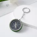 Detail of green rhinestone-studded aluminum alloy mini compass keychain on white background. - Green