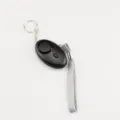 Macro view of black personal safety alarm featuring an LED light and a grey fabric wrist strap - Black