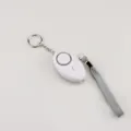 Close-up of white oval personal security alarm with keychain and grey wrist strap - White