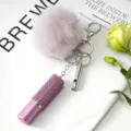 Primer plano de un llavero con pompón rosa, botella de diamantes y silbato de plata. - Juego de Colgantes de 3 Piezas / Rosa