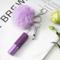 Gros plan d'un porte-clés flacon de parfum en strass violet avec pompon et sifflet - Ensemble de Pendentifs 3 Pièces / Violet