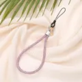 Close-up of pink 6mm rhinestone phone lanyard strap on soft beige fabric - Pink Purple