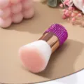 Primo piano del manico con strass viola e setole morbide di un pennello per polvere di unghie. - Rosso rosa