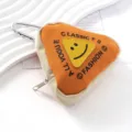Detalle de un estuche triangular de lona naranja con diseño de cara sonriente y mosquetón - Llavero / Naranja