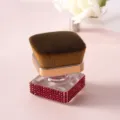 Gros plan détaillé du pinceau fond de teint de luxe avec strass rouges et poils doux. - Rouge