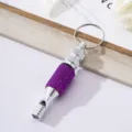 Macro view of a portable purple rhinestone-encrusted aluminum alloy survival whistle keychain - Purple