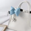 Close-up of a blue puffy leather bow keychain with a silver heart charm on a white bag - Sky Blue