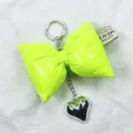 Detailed macro view of neon green leather bow keychain featuring a silver heart charm. - Fluorescent Green