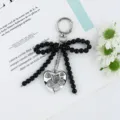 Primo piano di un ciondolo a cuore argento e un fiocco di perline nere su un portachiavi - Stile Cuore con Fiocco di Perline Nere / Nero
