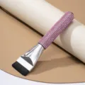 Macro detail of a flat makeup foundation brush featuring a pink rhinestone handle - Pink