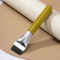 Close-up view of a flat foundation brush featuring a luxurious gold rhinestone handle. - Yellow