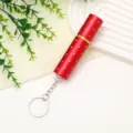 Detailed view of red refillable perfume bottle with rhinestone accents and silver keychain - Red