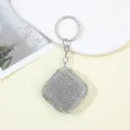 Nahaufnahme eines glitzernden Mini-Maßband-Schlüsselanhängers mit schicken Strasssteinen - Weiß