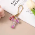 Close-up of a floral resin cross keychain with a pink tassel and gold chain pendant - Pink Yellow Dried Flower (Pink Tassel)