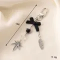 Creatieve zwarte strik sleutelhanger met blad- en veerhangers voor tassen en hoesjes - Elegant Zwarte Strik + Zilveren Blad