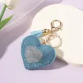 Detailed view of sparkly blue rhinestone heart keychain with gold ring and tassel - Lake Blue