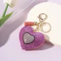 Close-up of sparkling rhinestone heart keychain with peach tassel and gold clasp - Pink