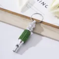 Detailed view of a silver aluminum survival whistle with green rhinestones and keyring. - Green