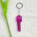Detail view of a purple key-shaped folding knife on a white textured background - Rose Red
