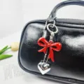 Elegant red bow and silver heart pendant keychain charm accessory shown on a black leather bag - Swallowtail Bow Pendant (02) / Red
