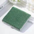 Primer plano detallado de una pitillera de metal con brillantes piedras de strass verde - Verde