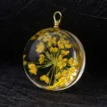 Close-up detail of a handmade clear glass pendant containing bright yellow dried flowers. - Gold Wire (P2016)