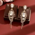 Elegant gold rhinestone dangle earrings with sparkling teardrop crystals and long tassels. - Gold