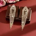 Close-up details of sparkling rhinestone long tassel earrings on display pads, shiny crystals. - Gold