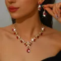 Detailopname van de rode kristallen bruidsketting en oorbellen set met gouden design. - Rood
