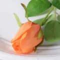 Single artificial orange rose bud with realistic silk petals and green leaves - Orange