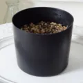 Black plastic flower pot designed specifically for artificial plants with pebbles inside. - Black