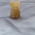 Close-up detail of a charming yellow crystal cat carving figurine, beautiful mineral gemstone craft. - Topaz