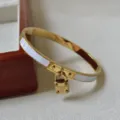 Nahaufnahme eines goldenen Edelstahlarmbands mit Vorhängeschloss und Gravur - Weiß