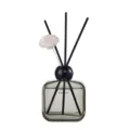Glass reed diffuser bottle with black cap, black sticks, and white flower for home decor. - Courtyard Gardenia