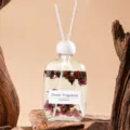 Nahaufnahme einer transparenten Glas-Duftstäbchen-Flasche gefüllt mit Trockenblumen. - Oud Rose