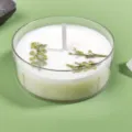 Close-up detail of scented tea wax candle in clear cup with dried green floral botanicals. - White / Gardenia White Tea