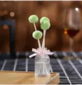 Fireless aroma reed diffuser with green fluffy ball and pink ribbon bottle detail view. - Hilton