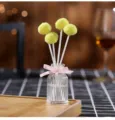 Flameless aroma diffuser bottle with yellow fluffy ball sticks and pink ribbon bow detail - Shangri-La