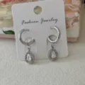 Elegante silberne Edelstahl Tropfen-Kristall-Creolen präsentiert auf einer weißen Karte - Wassertropfen-Creolen / Silber