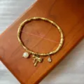 Vergoldetes Edelstahl-Bambusarmband mit Perlen- und Schleifenanhängern, Größe 60 mm - Schleife Perlen Anhänger Armreif / 60mm / Gold
