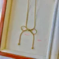 Makro-Detailansicht der eleganten goldenen Schleifen-Halskette mit Maßen 41mm und 50mm. - Schlangenkette Schleife Halskette / Gold
