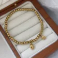 Elegantes goldenes 3mm Edelstahl Perlenarmband mit zwei dekorativen Lotuskapsel Anhängern - Lotusblüten-Stil (16cm)