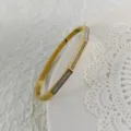 Eleganter goldfarbener Edelstahlreif mit Perlmutt-Inlay und funkelnden Zirkoniasteinen. - Gold