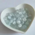 Close-up detail of light blue cat's eye round beads in a heart dish, perfect for DIY crafts. - Straight Hole (Through Hole) / Synthetic White Cat Eye