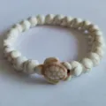 Close-up of a white turquoise beaded bracelet with a decorative turtle charm detail. - White Sea Turtle