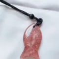 Close-up detail shot of the sparkling pink crystal fish pendant with black cord accessory. - Strawberry Quartz
