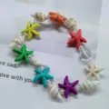 Detailed view of a colorful beach bracelet with starfish and seashell charms on beads. - Starfish + Conch