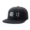 Close-up detail of the black flat brim baseball cap featuring white city embroidery and smiley. - Adjustable / Style 11